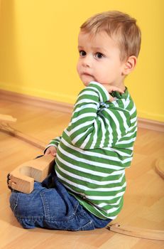 Cute european toddler playing with toy train in kindergarten.