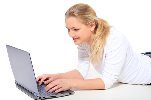 Attractive blond woman lying on floor using notebook computer. All on white background.