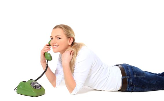 Attractive blond woman making a phone call while lying on floor. All on white background.