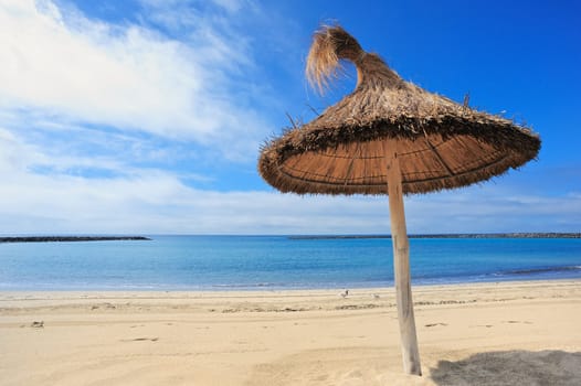 Straw parasol on the sandy sea beach