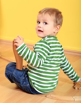 Cute european toddler playing with toy train in kindergarten.