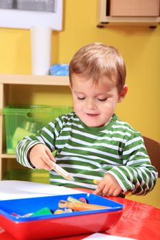 Cute caucasian toddler drawing a picture in kindergarten.