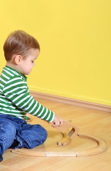 Cute european toddler playing with toy train in kindergarten.