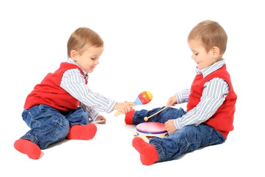 Cute caucasian twin brothers playing with music instruments. All isolated on white background.