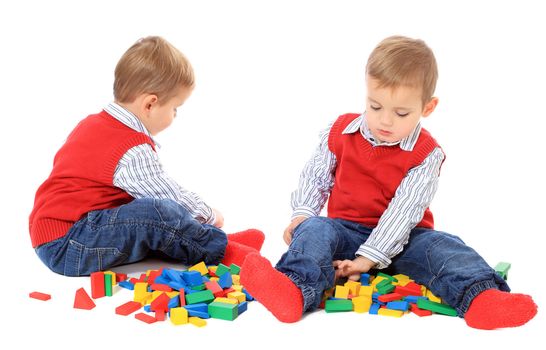 Cute caucasian twin brothers playing with colored bricks. All isolated on white background.