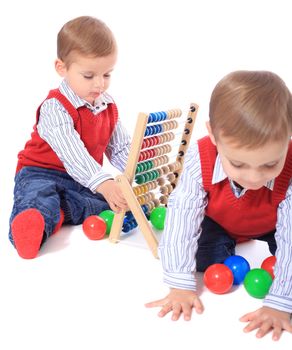 Cute caucasian twin brothers playing with toys. All isolated on white background. Foreground in very light grey.