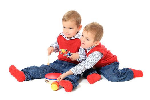 Cute caucasian twin brothers playing with music instruments. All isolated on white background.