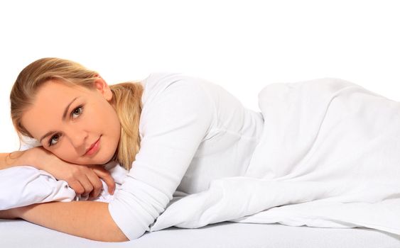 Attractive blond woman lying in bed. All on white background.