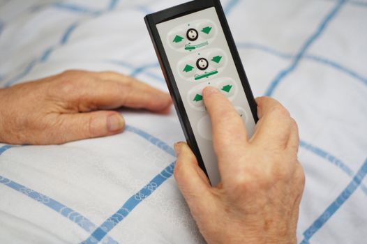 Hands of a care-dependent person holding remote control of an adjustable bed.