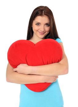 Attractive teenage girl holding red heart-shaped pillow. All on white background.