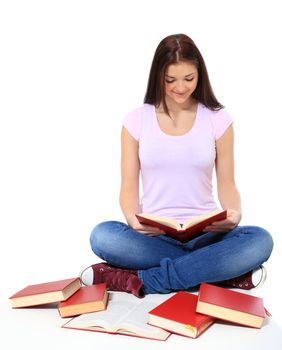 Attractive teenage girl sitting on the floor, reading a book. All on white background.