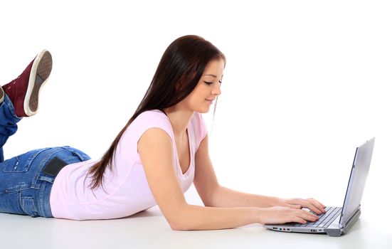 Attractive teenage girl lying on the floor, using notebook computer. All on white background.