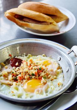 Fried egg with pork and sausage in hot pan, Breakfast in Thai style