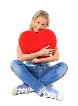 Attractive young scandinavian woman hugging a heart-shaped pillow. All on white background.