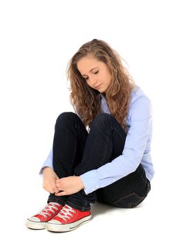 Sad young girl sitting on the floor. All on white background.
