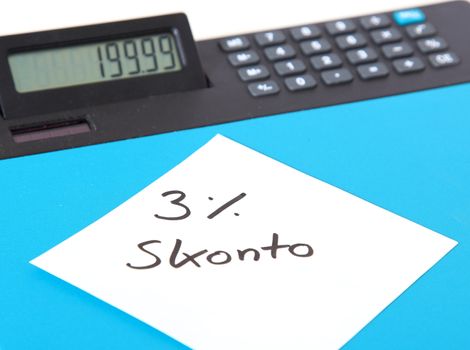 Piece of paper showing the showing the german term 3% Skonto (english: 3% discount) lying on a calculator