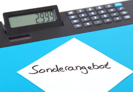 Piece of paper showing the showing the german term Sonderangebot (english: special offer) lying on a calculator