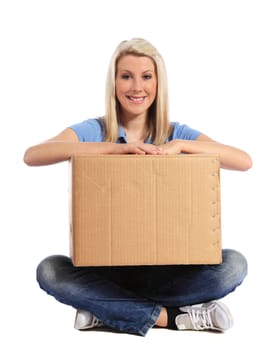 Attractive young woman sitting on floor holding moving box. All on white background.