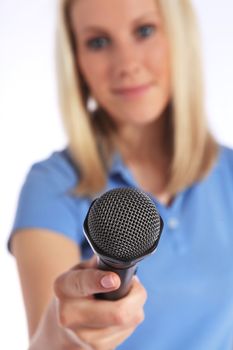 Attractive young interviewer holding a microphone. Selective focus on microphone in foreground. All on white background.