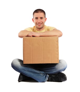 Attractive young man sitting on the floor and holding a moving box.
