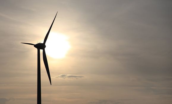 Silhouette of a wind power plant in front of sunset.