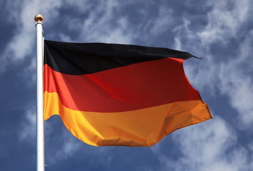 German flag in front of light cloudy sky.