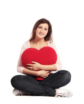 Attractive young woman holding a heart-shaped pillow. All on white background.