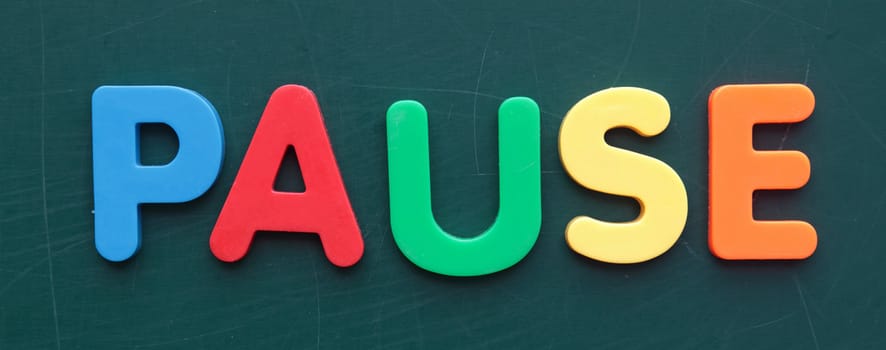 The term pause in colorful letters on a blackboard.