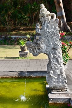 Fountain with traditional Balinese stone dragon image statue in Goa Lawah Bat Cave temple, Bali, Indonesia