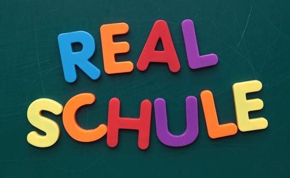 The german term Realschule (like Highschool) in colorful letters on a blackboard.