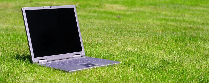 Notebook computer lying on green grass.