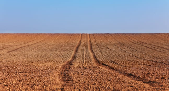 Tracks of a tractor in a bare field in spring.