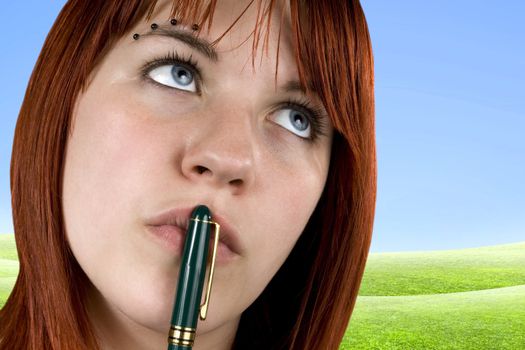 Cute girl with redhair pensive with pen on her lips.