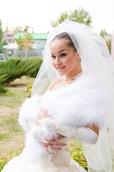 a beautiful bride smiles and covers with a cape