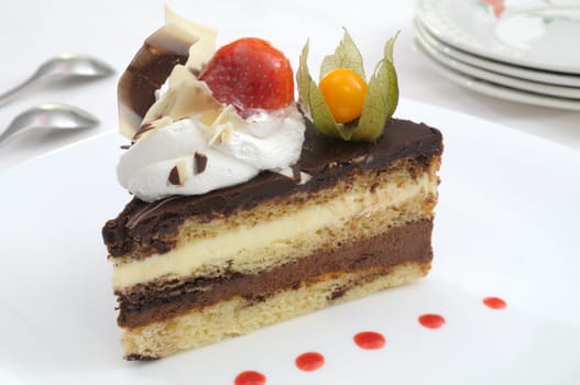 Chocolate layer cake slice decorated with a strawberry and a winter cherry