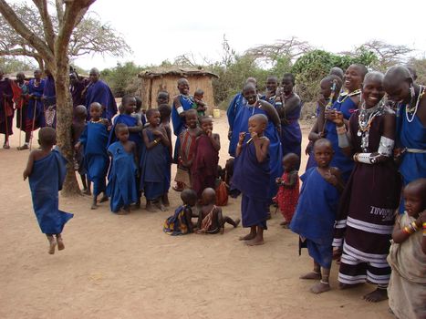 Masai performance in a traditional Masai village. Women with children singing and watching their men performance. Eastern Kenya Africa 2007.