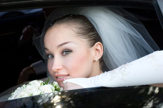 happy bride with flower bouquet in the car