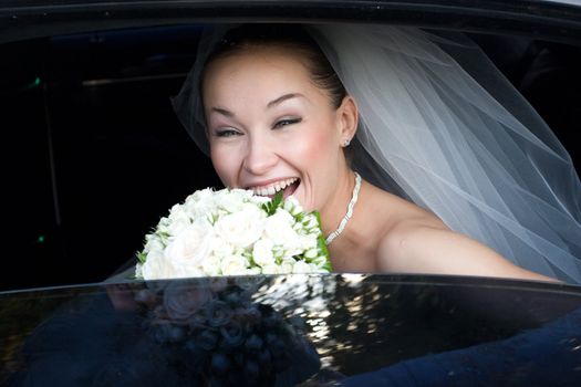 happy bride with flower bouquet in the wedding car