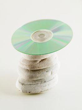 cd disc balanced on four beach stones on white