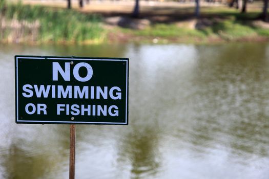 Warning sign, no swimming or fishing in this pond.