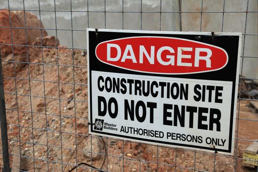 Warning sign on a construction site fence.