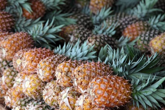 Pile of ripe pineapples on a market stall.