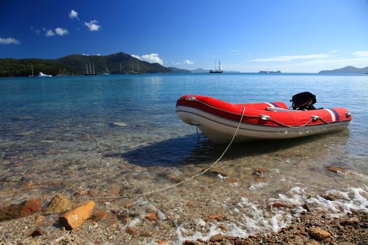 Red rubber boat tightened at waterside.