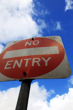 No entry sign in front of light cloudy sky.