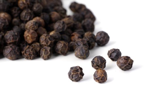 Detail shot of a pile of black peppercorns. All isolated on white background.