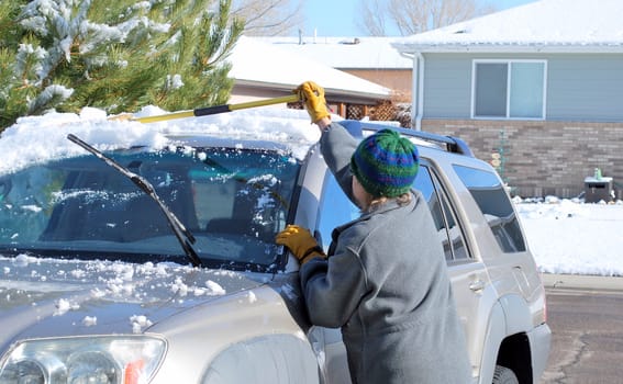 Female clearing snow off her suv.