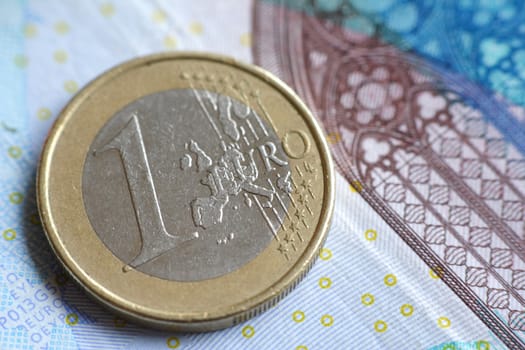 A single euro coin on a banknote.