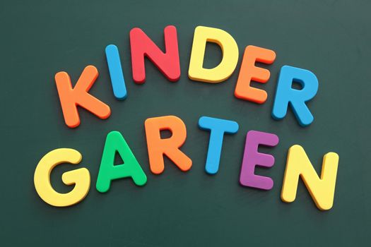 The word kindergarten built out of colored bold letters on a blackboard.