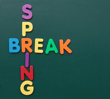 Several bold multicolored letters build the term spring break on a blackboard.