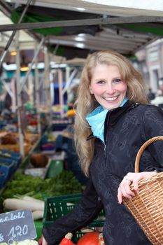 Smiling woman buys fruit and vegetables on the market.